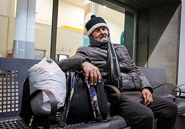 Juan se sienta al lado de sus pertenencias.