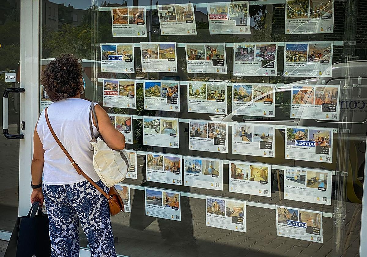 Una mujer observa ofertas en el escaparate de una inmobiliaria de la capital en una imagen de archivo.