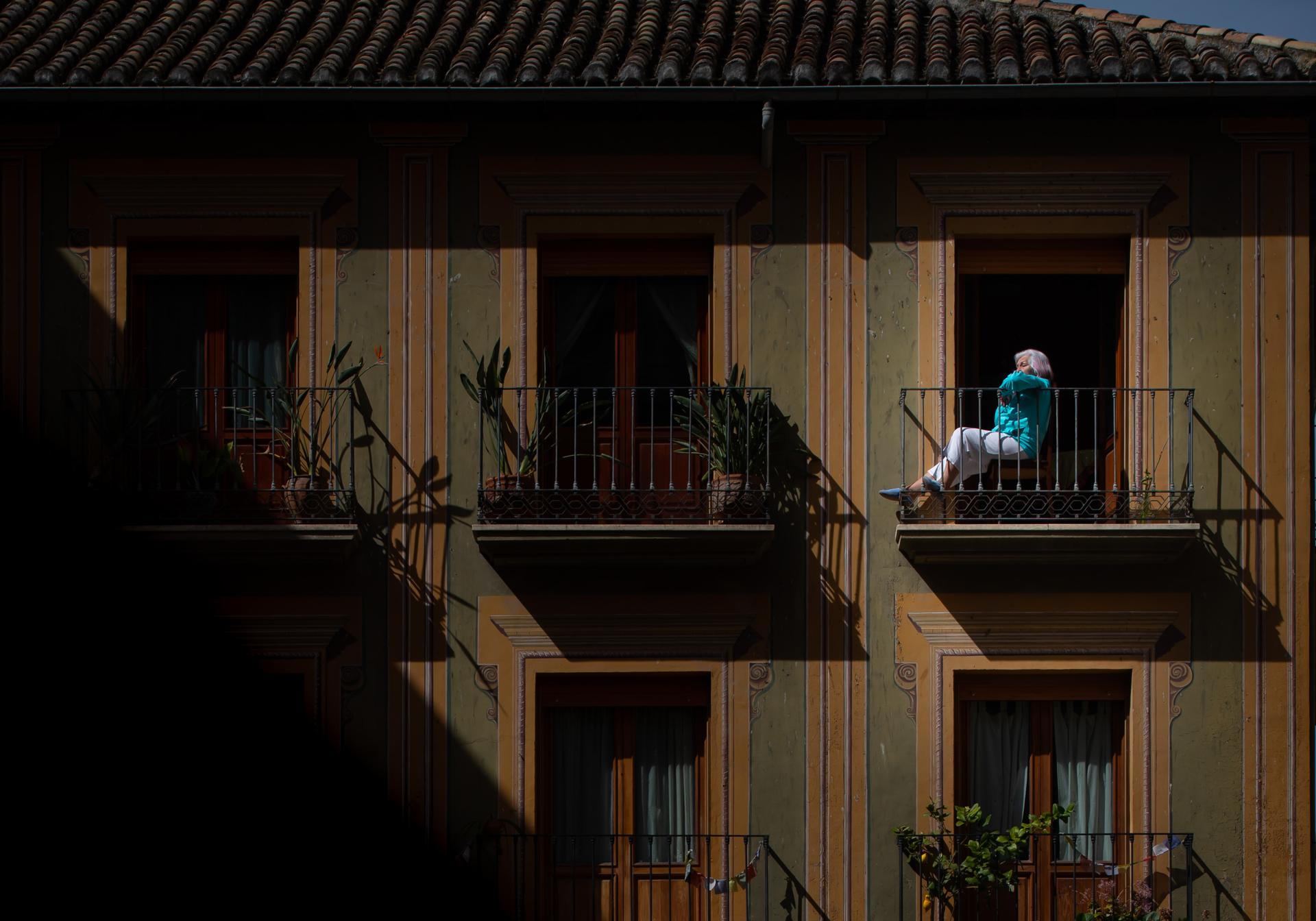 Una vecina toma el sol en una terraza de la plaza de las Pasiegas.