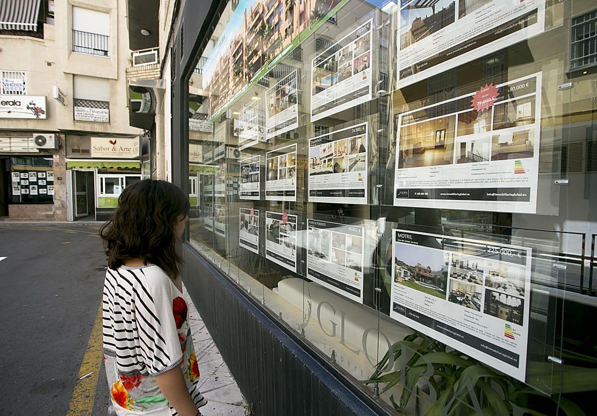 Foto de archivo de una joven mirando ofertas en una inmobiliaria.