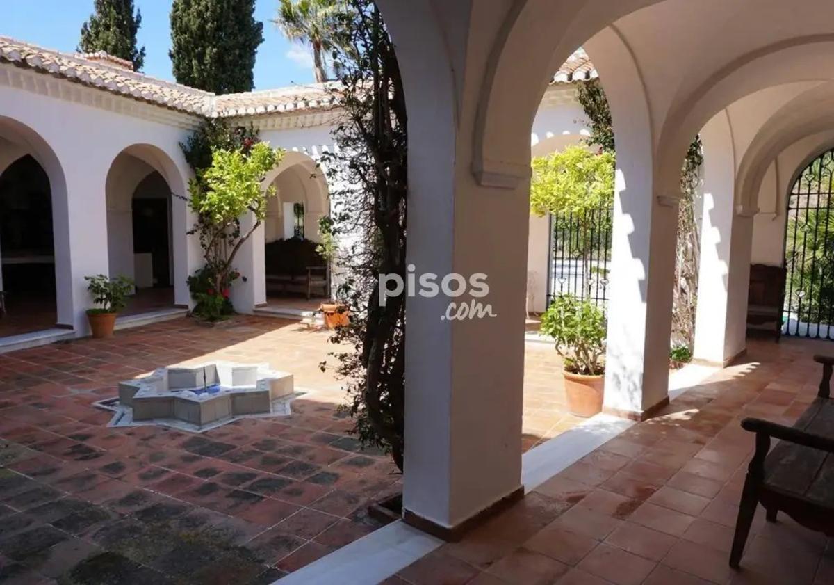 Imagen principal - Una de las terrazas, jardín y entrada principal de la vivienda.