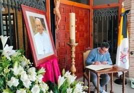 Un hombre firma en el libro de condolencias.