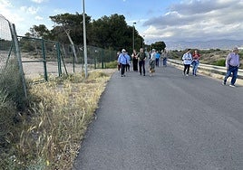 Vecinos caminan por el camino que lleva a la playa de El Alquián.