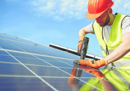 Un técnico instala paneles solares en un tejado.