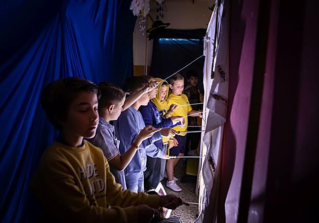 Los alumnos generando las sombras chinescas detrás de la pantalla.