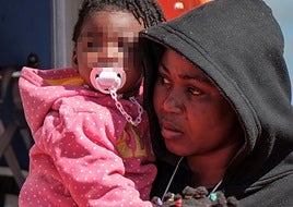 Una mujer lleva en brazos a los dos bebés que viajaban en tras cuatro días en el mar.