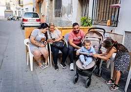 Manuela juega con Yerai en presencia de sus familiares, sentados en sus sillas en la calle Hoyos de Santa Fe.