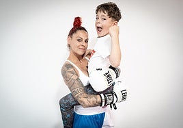 La boxeadora Sandra Muñoz carga en brazos a su hijo Víctor en el gimnasio.