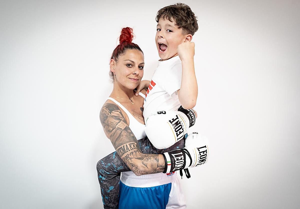 La boxeadora Sandra Muñoz carga en brazos a su hijo Víctor en el gimnasio.
