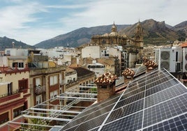 Dos instaladores trabajan en los paneles solares en el tejado de un edificio de viviendas.