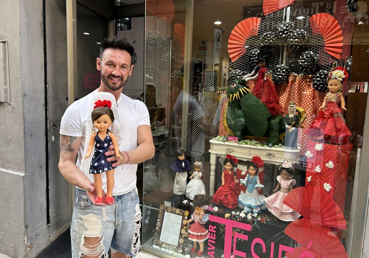 El peluquero sujeta a una de sus Nancy frente a su escaparate.