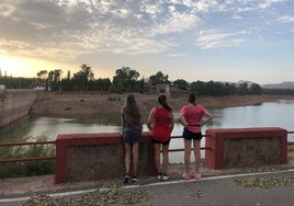 Tres jóvenes contemplan una cola del pantano del Guadalén.
