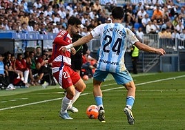 Manu Trigueros juega un balón ante la presión de un futbolista del Málaga en La Rosaleda.