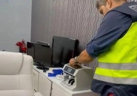 Un agentes de Policía interviene una máquina de contar billetes.
