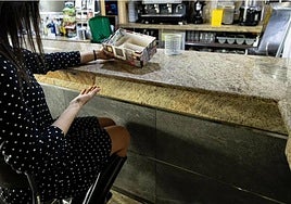 Una clienta muestra una caja colocada de forma temporal en un local afectado, así como la barra rota.