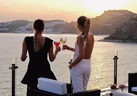 Dos personsa en un sky bar frente a la costa mediterránea.