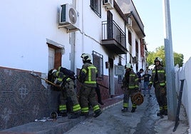Bomberos en una de las viviendas quemadas en Pinos Puente.