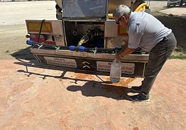 Un vecino llena una botella de agua del camión.