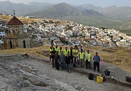 Zona de la excavación, el equipo de voluntarios con las autoridades y detrás una vista de Bedmar.