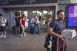En primer plano, Álex, pasajero afectado. Detrás, otros viajeros saliendo de la estación.