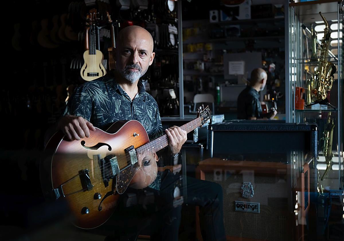 Quini Almendros posa con una de las cien guitarras que tiene en su negocio.