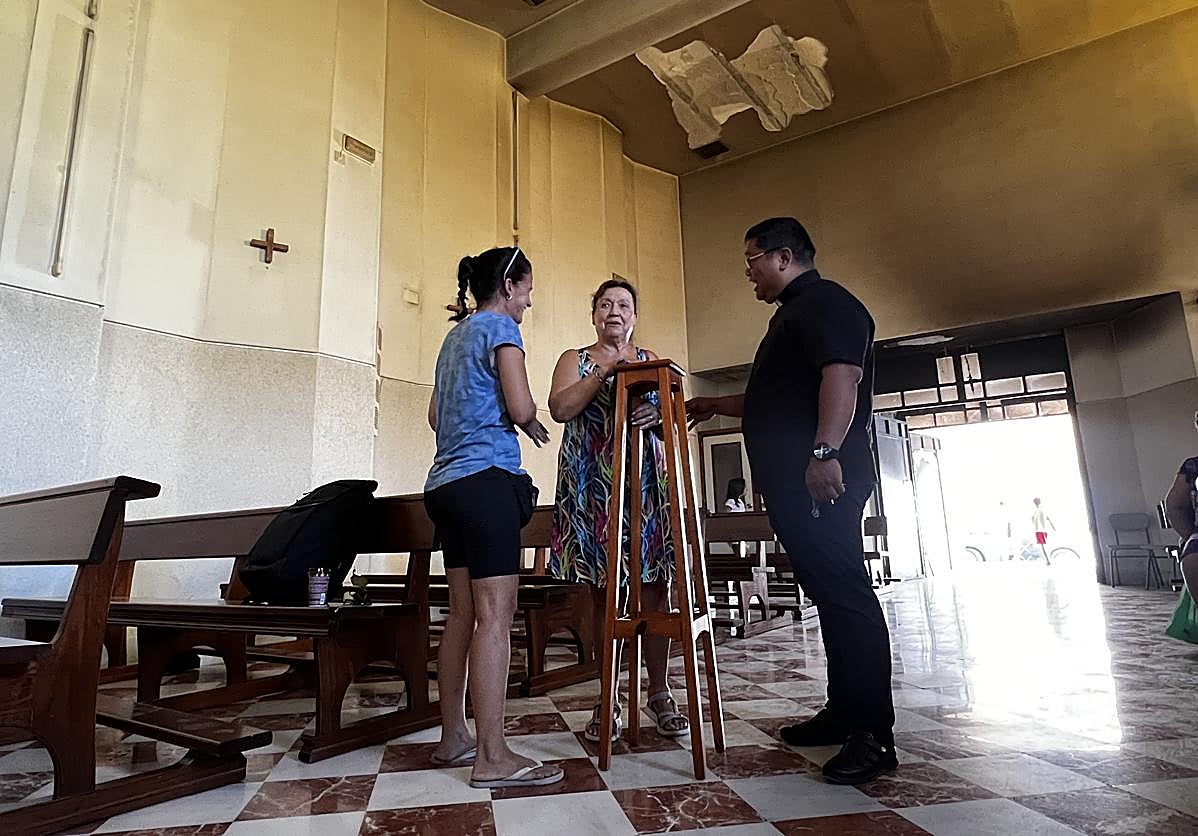Los vecinos limpian los enseres que quedan en la iglesia que permanece con las paredes calcinadas