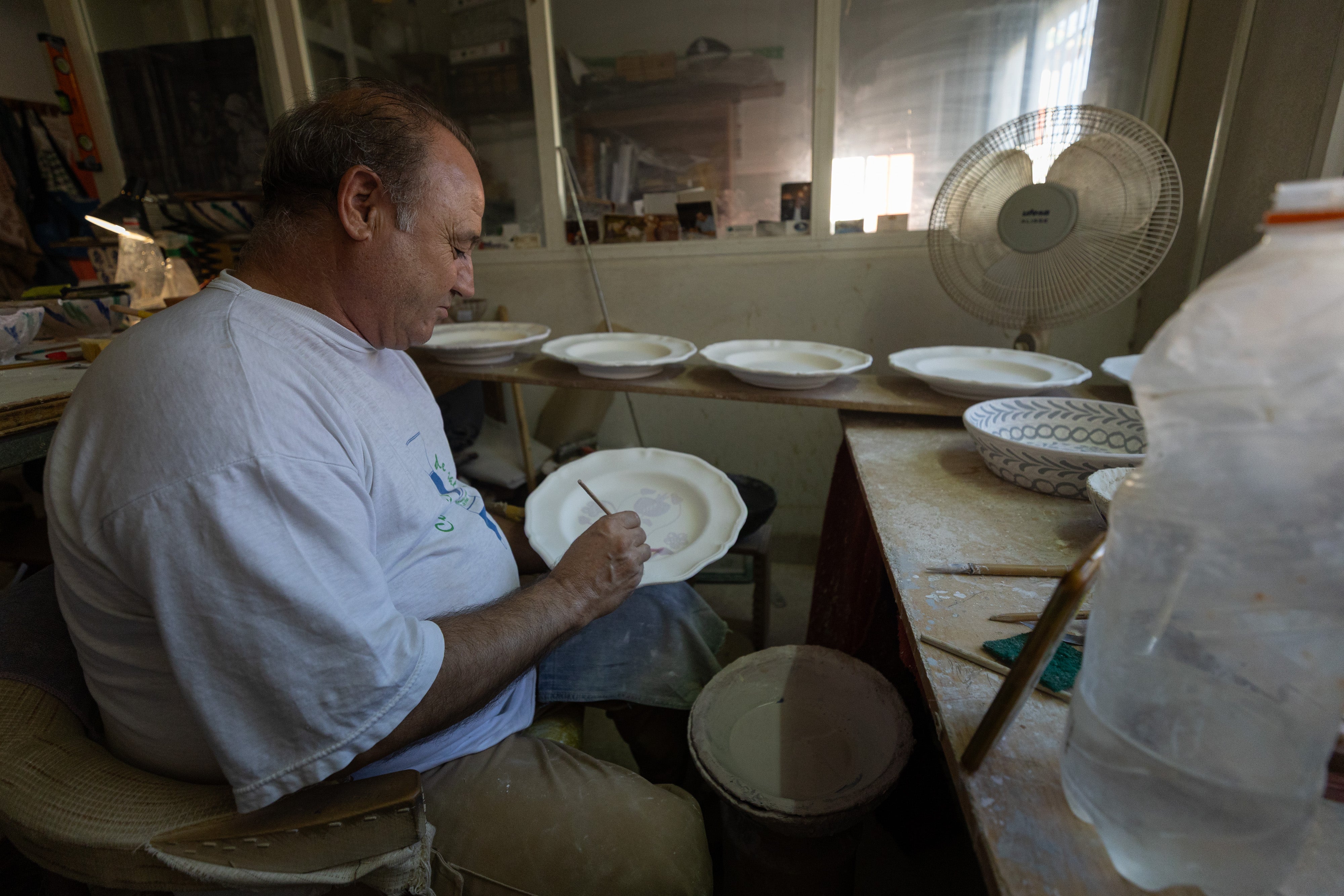 Imagen secundaria 1 - Manuel España, alfarero de toda la vida, decora un plato. Los lebrillos y los cuencos son los productos más demandados de la fábrica
