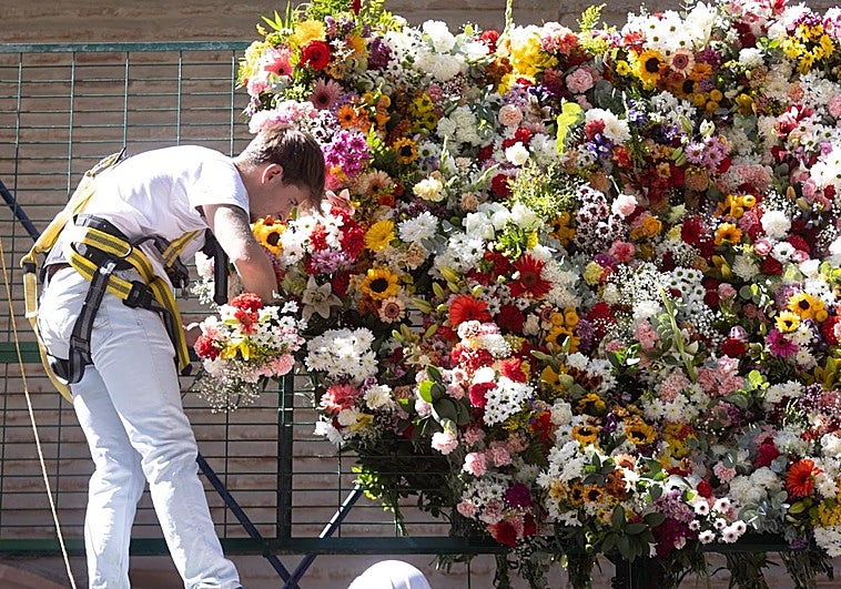 Operarios colocan las flores en la basílica de la Virgen de las Angustias.