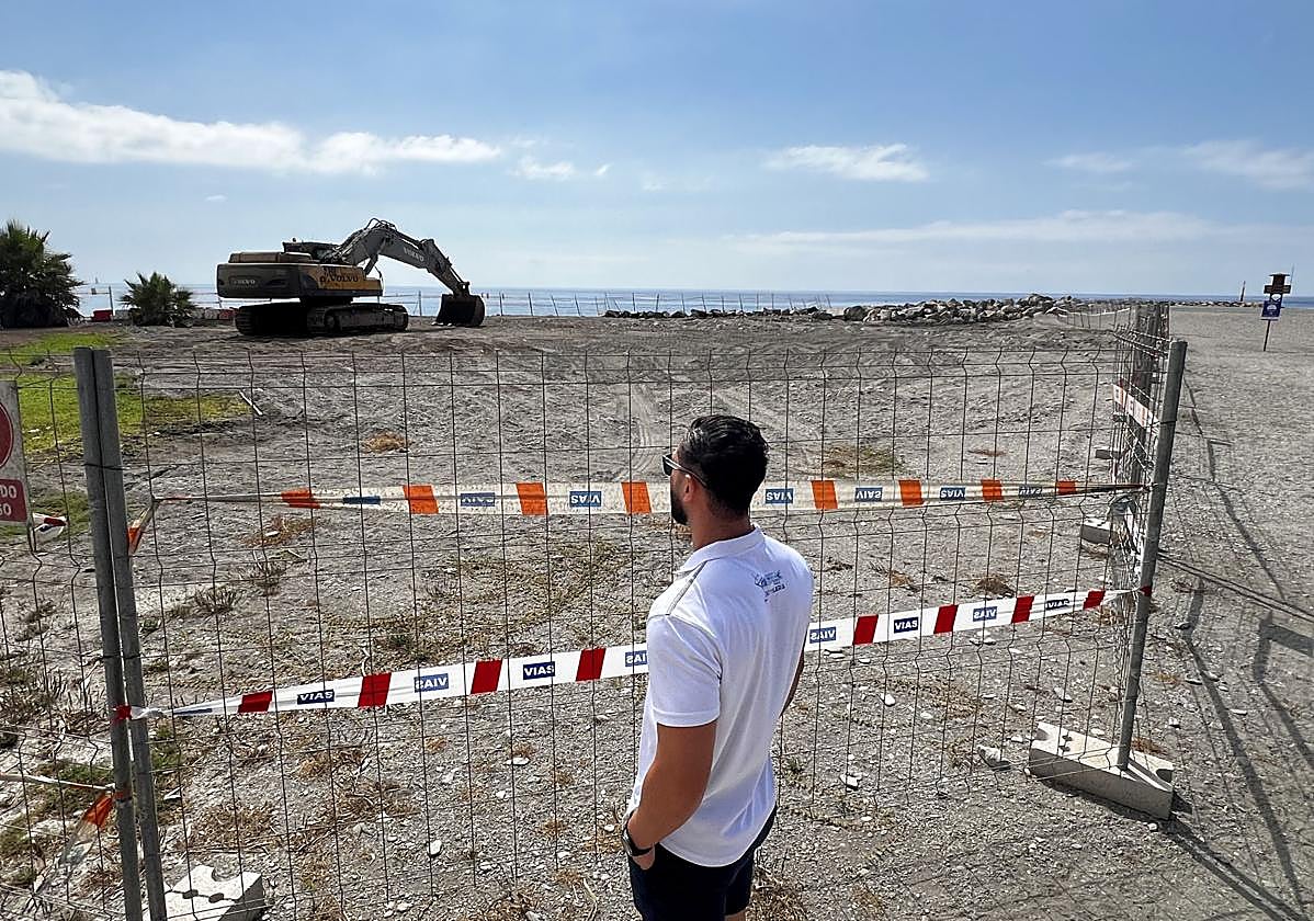 Un viandante observa la máquina parada y el espigón de fondo.