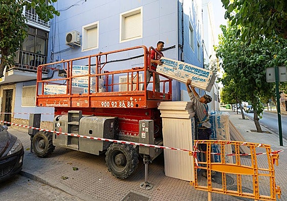 Dos trabajadores preparan el material para el aislamiento térmico de un bloque