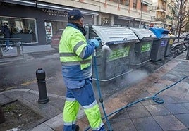 Un operario del Ayuntamiento limpia unos contenedores en las calles de Granada.