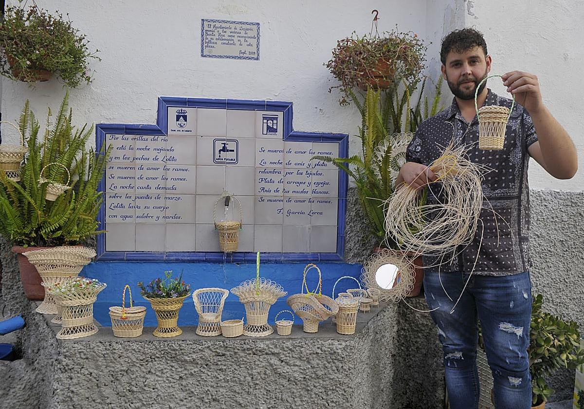 Enrique Carmona mostrando algunos de sus objetos en miniatura tejidos con fibra junto al pilar de la Placeta de Santa Ana