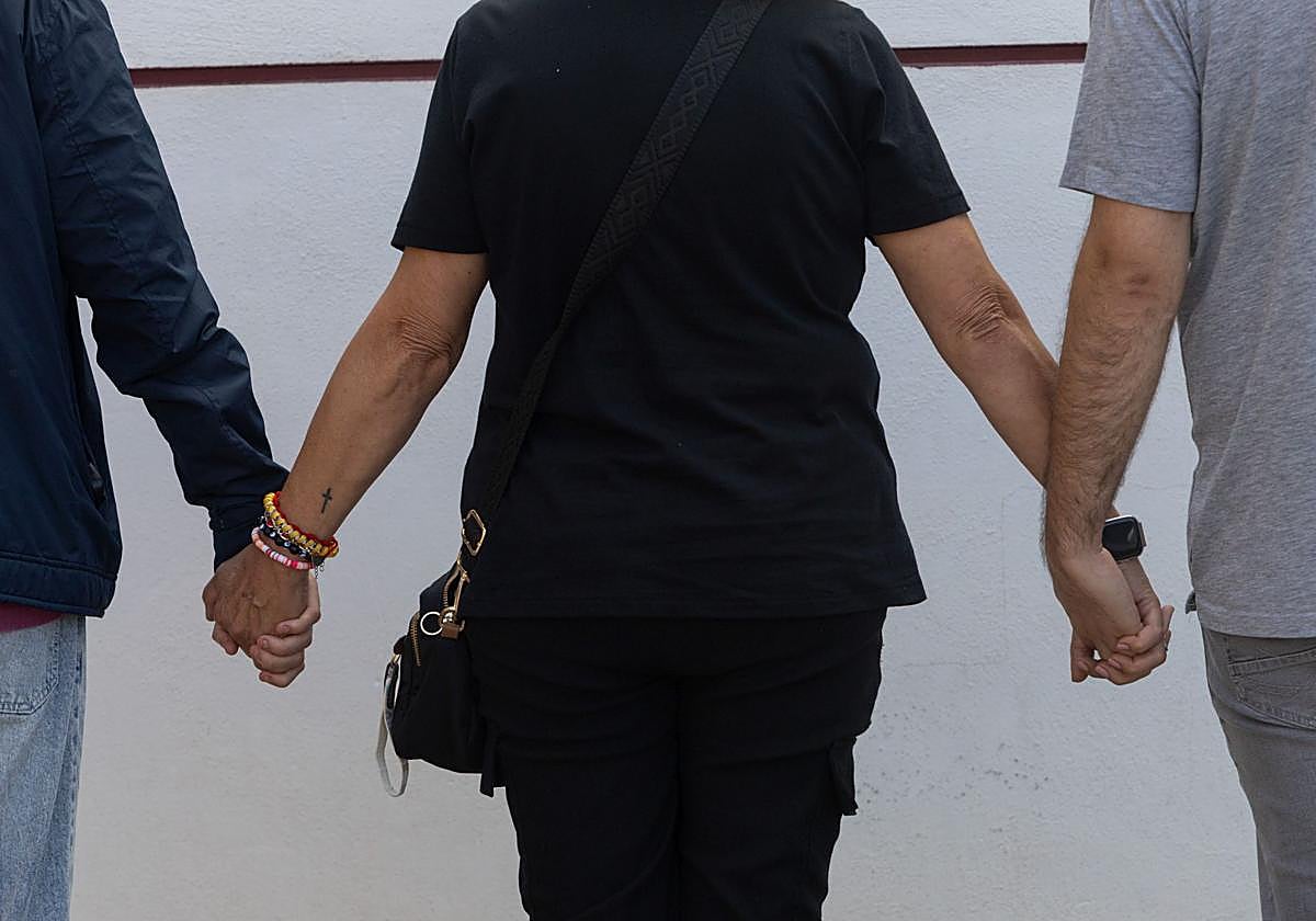 Ana, mujer que fue apuñalada por su marido este año, coge de la mano a sus hijos.