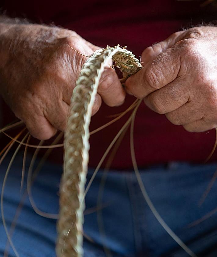 Imagen secundaria 2 - Las manos de Manuel muestran cómo trenzar esparto y arriba una reproducción de la Catedral de Granada con esparto.