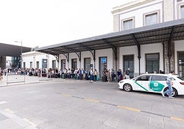 Viajeros esperan en la puerta de la estación para coger un taxi
