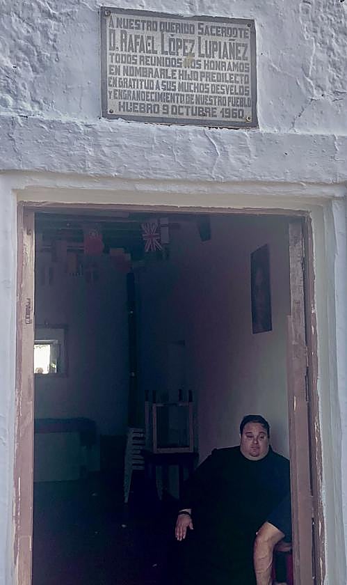 El nuevo párroco de Huebro, Juan José Muñoz, el domingo pasado, bajo la placa de 1960 que recuerda al cura Rafael López Lupiáñez.