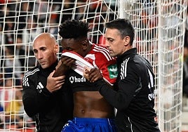 Alberto Lara y Dioni González, del cuerpo médico, ayudan a caminar a Bouldini tras su lesión.