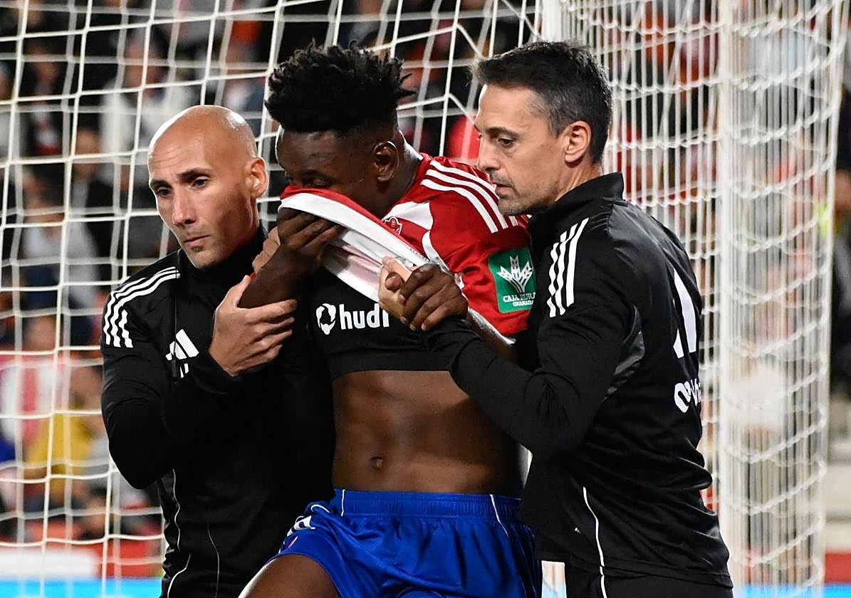 Alberto Lara y Dioni González, del cuerpo médico, ayudan a caminar a Bouldini tras su lesión.