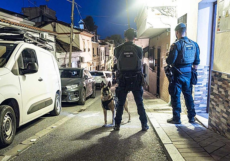 La Guardia Civil introduce en el vehículo policial a uno de los detenidos.