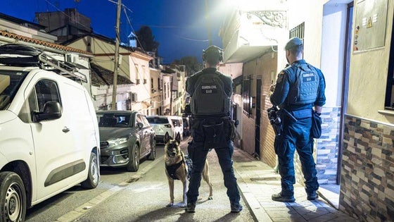 La Guardia Civil introduce en el vehículo policial a uno de los detenidos.