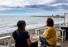 Unas vecinas observan en la terraza de un chiringuito, el espigón terminado.
