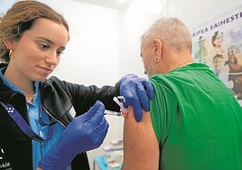 Una sanitaria inyecta una dosis de la vacuna de la gripe a un ciudadano.