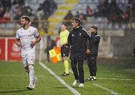 Pacheta sigue el partido desde la banda bajo la lluvia.