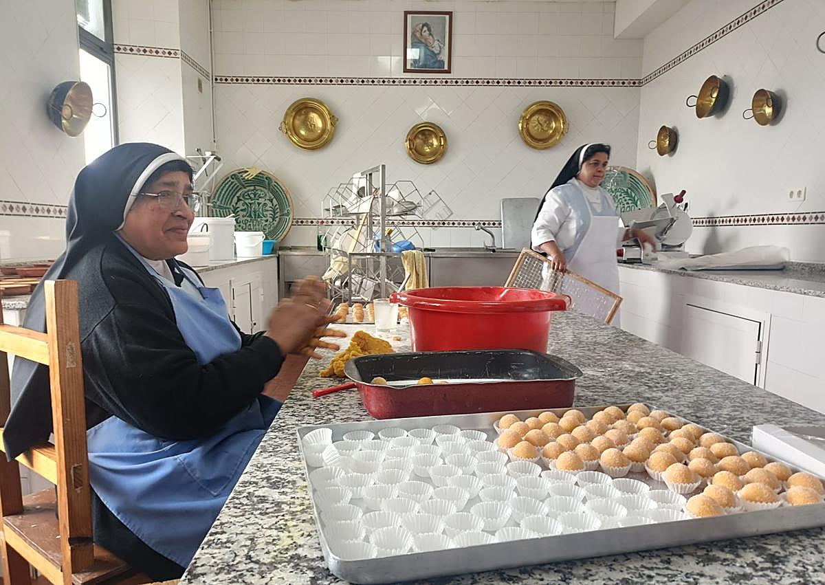 Imagen secundaria 1 - La madre superiora de las carmelitas Descalzas muestra una caja con mantecados. Dos hermanas de las Comendadoras elaboran dulces.
