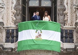 El presidente de la Junta, Juanma Moreno, despliega la bandera en el balcón de San Telmo, junto a la periodista Isabel Jiménez