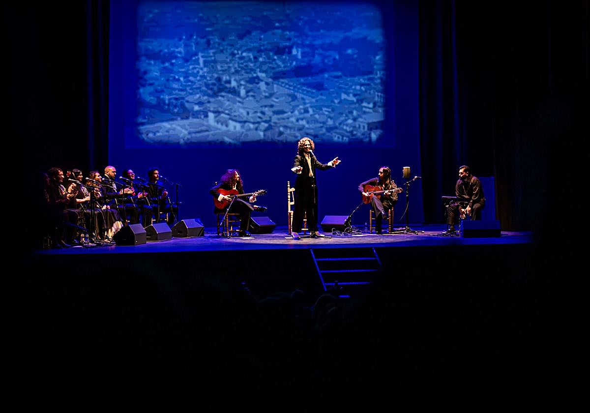 Kiki Morente, sobre el escenario con una imagen antigua de Granada detrás.