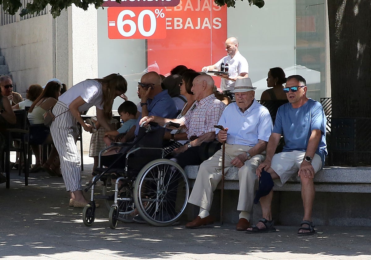 Varios acalorados transeúntes se refugian en la sombra