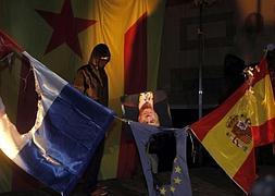 Encapuchados queman una bandera española y una foto del Rey. / Efe