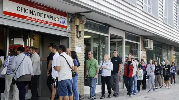 Varias personas hacen cola en una oficina de empleo.