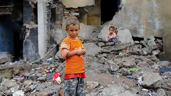 Unos niños sirios refugiados juegan entre los escombros de una casa 